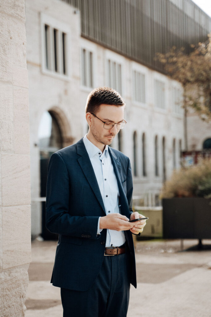 Frank Steeger mit Smartphone vor einem Bürogebäude